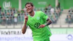 Der VfL-Wolfsburg-Spieler Wout Weghorst jubelt und zeigt lächelnd mit dem Finger in die Höhe.