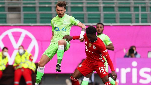 Ein Spieler des VfL Wolfsburg im Duell um den Ball mit einem Spieler des FC Bayern München.