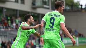 Die Wölfe des VfL Wolfsburg Wout Weghorst und Renato Steffen haben sich umarmt und laufen auf die anderen jubelnden Spieler zu. 