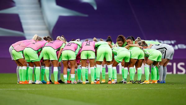 Die Frauenmannschaft des VfL Wolfsburg steht beim Aufwärmen zur Besprechung gebückt in einem Kreis.