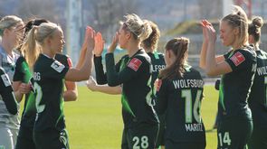 Die Spielerinnen des VfL Wolfsburg klatschen sich ab und feuern sich an.