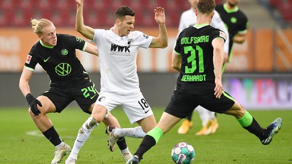 Die beiden VfL-Wolfsburg-Spieler Xaver Schlager und Yannick Gerhardt kämpfen mit einem Gegenspieler um den Ball.