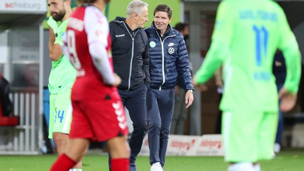 VfL-Wolfsburg-Trainer Oliver Glasner und SC-Trainer Christian Streich gemeinsam über das Spielfeld und unterhalten sich.