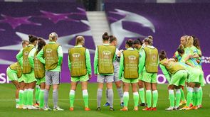 Die Frauenmannschaft des VfL Wolfsburg steht vor dme Spiel im Kreis. Die Spielerinnen tragen Leibchen mit dem Logo und Schriftzug der UWCL 