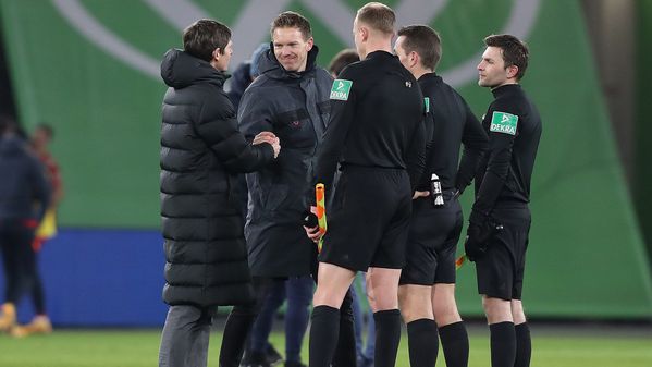 VfL-Wolfsburg-Trainer Oliver Glasner und Leipzig-Trainer Julian Nagelsmann sowie drei Schidesrichter stehen nach dem Spiel gemeinsam auf dem Rasen und unterhalten sich.