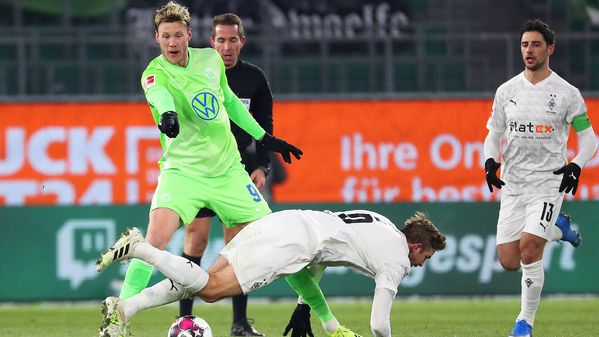 Wout Weghorst zeigt auf einen fallenden Gegenspieler aus Mönchengladbach.