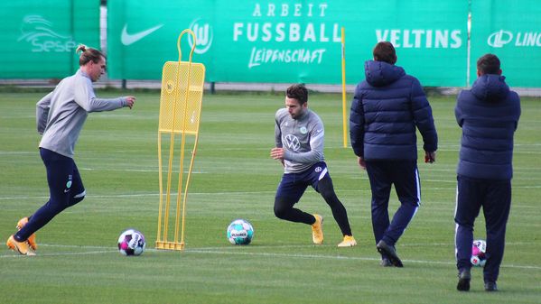Die VfL-Spieler Klaus und Steffen laufen im Training mit dem Ball um Männchen herum. 