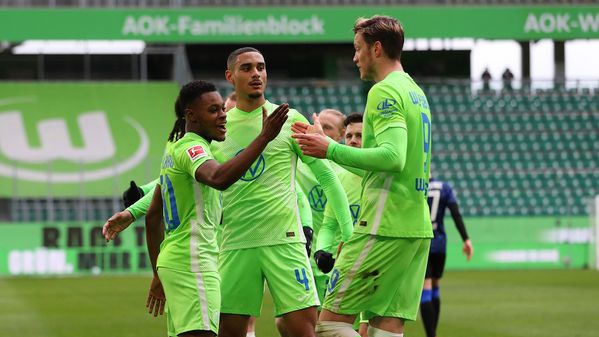 Die VfL-Wolfsburg-Spieler Ridle Baku, Maxence Lacroix und Wout Weghorst stehen beisammen und jubeln.